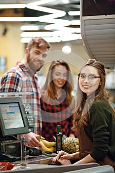 Cheerful cashier woman on workspace in supermarket