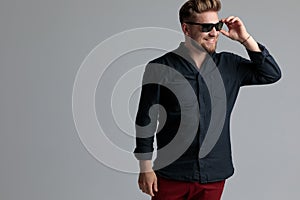 Cheerful casual man laughing and adjusting his sunglasses