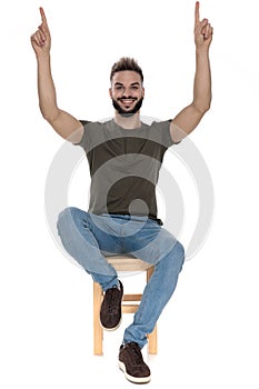 Cheerful casual man pointing up and smiling