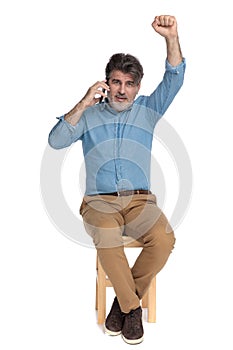 Cheerful casual man talking on his phone and celebrating