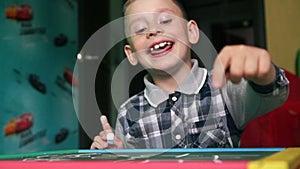 Cheerful Caucasian boy preschooler learning to write on the blackboard with chalk at home. Writes words and laughs with pleasure.