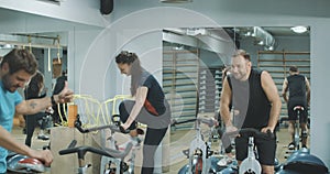 Cheerful caucasian coach welcoming men and women in gym. Group of healthy slim people start exercising on cycling bikes