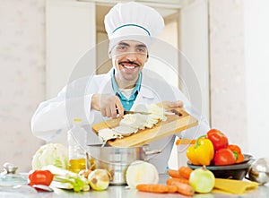 Cheerful caucasian cook does veggy lunch