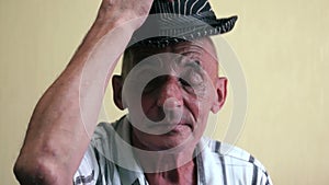 Cheerful caucasian elderly man over 70 greets and takes off his hat from his bald head. Pensioner greets by taking off his hat. Se