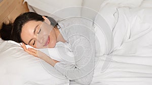 Cheerful caucasian millennial female with closed eyes sleeping on comfortable bed, enjoy softness, weekend