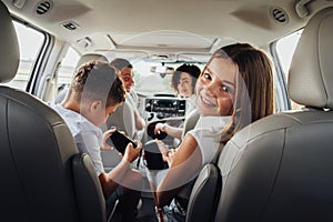 Cheerful Caucasian Teenage Girl Smiles Into the Camera While Sitting in Minivan Car with Her Brother, Mother and Father