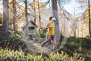 Cheerful caucasian woman on a hike running trough the autumn forest, sun rays shining trough the trees