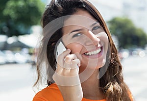 Cheerful caucasian woman in a orange shirt at phone