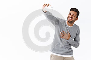 Cheerful and charismatic european guy with bristle talking to friend via internet messanger app, holding smartphone