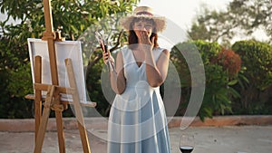 Cheerful charming young woman holding painting tools sending air kiss in slow motion looking at camera. Portrait of