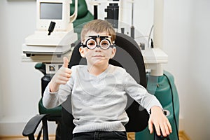 Cheerful child boy in glasses checks eye vision pediatric ophthalmologist