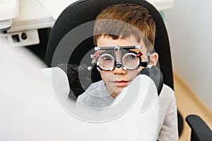 Cheerful child boy in glasses checks eye vision pediatric ophthalmologist