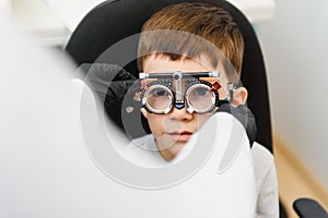 Cheerful child boy in glasses checks eye vision pediatric ophthalmologist