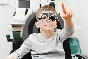 Cheerful child boy in glasses checks eye vision pediatric ophthalmologist