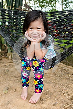 Cheerful child enjoying and relaxing in hammock, outdoor on summer day.