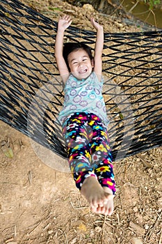 Cheerful child enjoying and relaxing in hammock, outdoor on summer day.