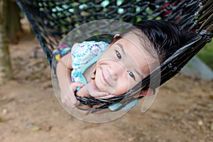 Cheerful child enjoying and relaxing in hammock, outdoor on summer day.