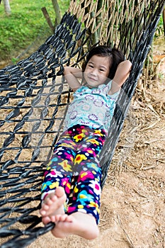 Cheerful child enjoying and relaxing in hammock, outdoor on summer day.