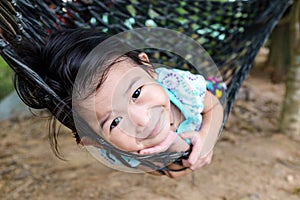 Cheerful child enjoying and relaxing in hammock, outdoor on summer day.