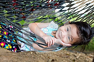 Cheerful child enjoying and relaxing in hammock, outdoor on summer day.