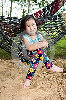 Cheerful child enjoying and relaxing in hammock, outdoor on summer day.