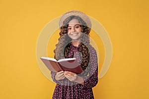 cheerful child with frizz hair read book on yellow background