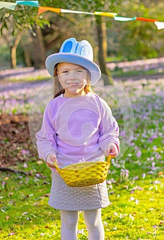 cheerful child girl in hat with rabbit ears o and a basket with Easter eggs at the party in garden