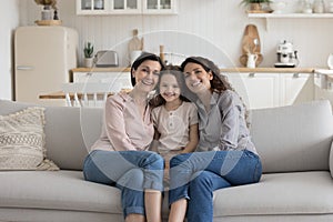 Cheerful child girl, mother and grandma sitting close on couch