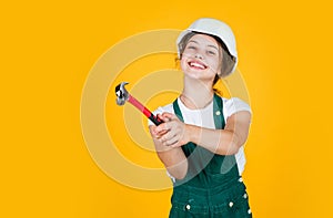 Cheerful child laborer using building uniform and hammer tool, tool shop