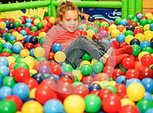 Cheerful child playing inside ball pit swimming pool - Little girl having fun in baby playground indoor - Childhood concept -