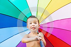 Cheerful child turning big colorful umbrella