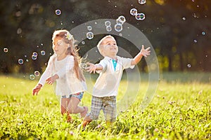 Cheerful children chase bubbles