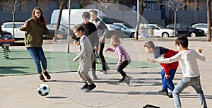 Cheerful children are jogning with ball on the street