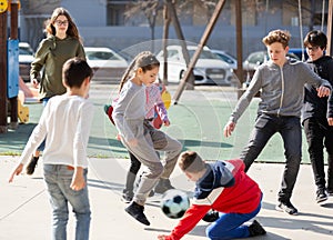 Cheerful children are jogning with ball on the street