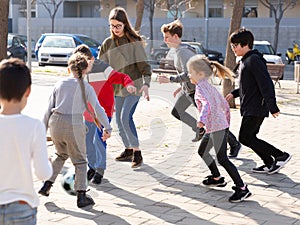 Cheerful children are jogning with ball on the street