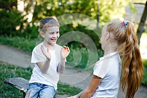 Cheerful children are playing in the park on a green bench.