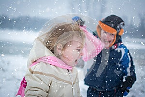 Cheerful children playing together on snowy winter day.