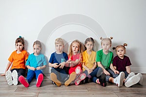 Cheerful children sitting on a floor near the wall