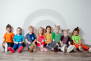 Cheerful children sitting on a floor near the wall