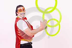 Cheerful circus performer skillfully juggling a number of rings isolated on white background