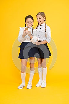 Cheerful classmates with smartphone. little girls in school uniform. back to school. educational blog. new technology in