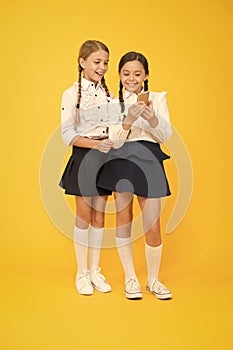 Cheerful classmates with smartphone. little girls in school uniform. back to school. educational blog. new technology in