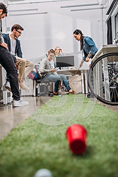 cheerful colleagues playing in mini golf at modern