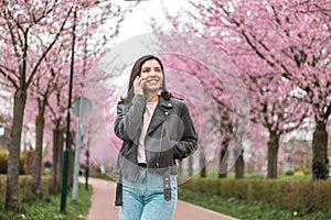 cheerful and confident young woman of mixed races ethnicity on phone with beloved friends or relatives walking alone in