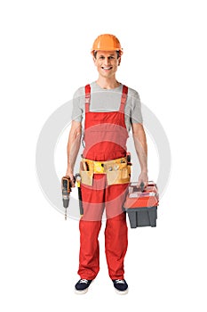 Cheerful construction worker in uniform holding toolbox and drill