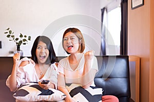 Cheerful couple asian women watching TV feeling having fun .together at home