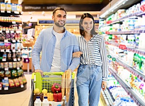 Cheerful couple with the cart shopping in supermarket