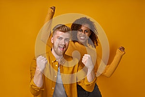 Cheerful couple clenching fists like winners or happy to achieve goal