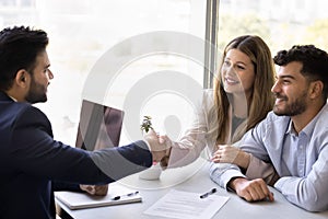 Cheerful couple of clients shaking hands with Indian lawyer man