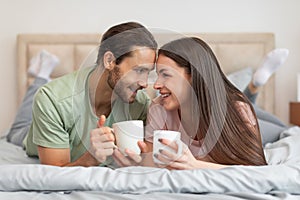 Cheerful couple with coffee, sharing moment in bed